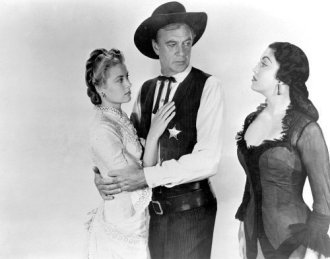 Marshal Will Kane (Gary Cooper) and new bride Amy Fowler Kane (Grace Kelly) in a publicity shot with his ex-lover Helen Ramirez (Jurado) glaring. No scene like this occurs in the film. 